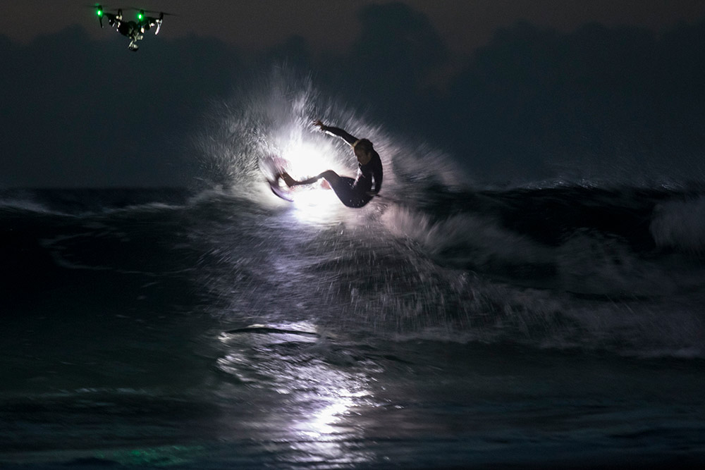 Night surfer lit with drone lighting