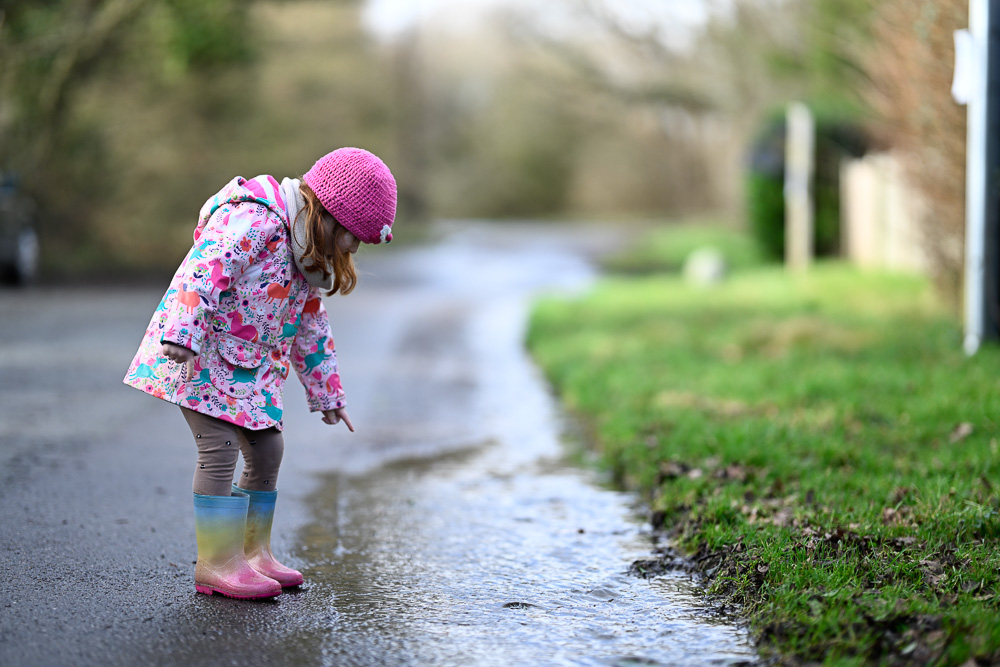 Daughter playing in puddles, sample image shallow depth f field Nikon f1.2 85mm lens