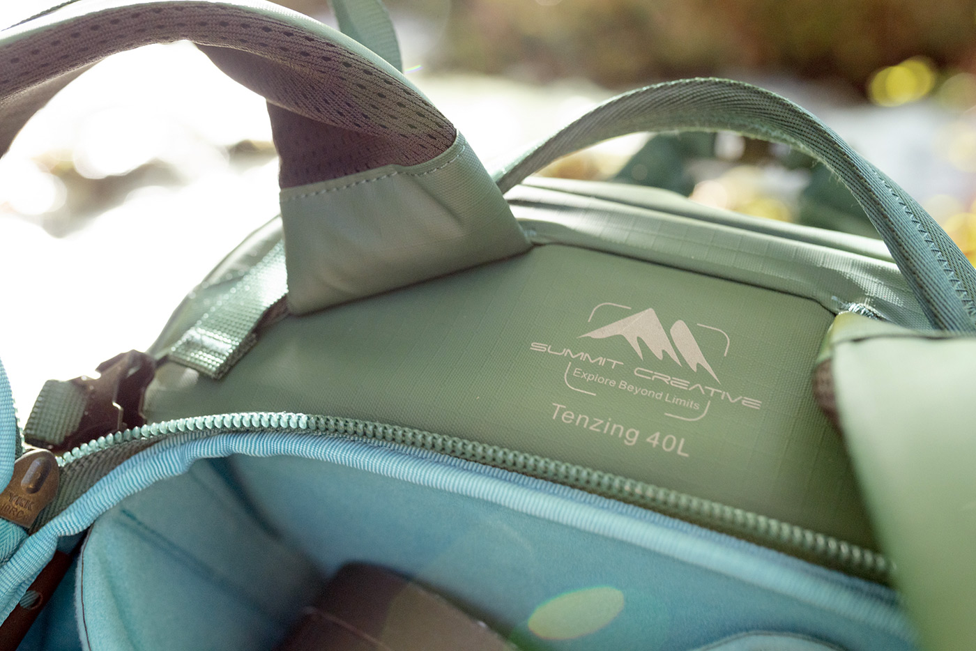 Close-up shot of the Summit Creative Tenzing 40L backpack logo and top of bag