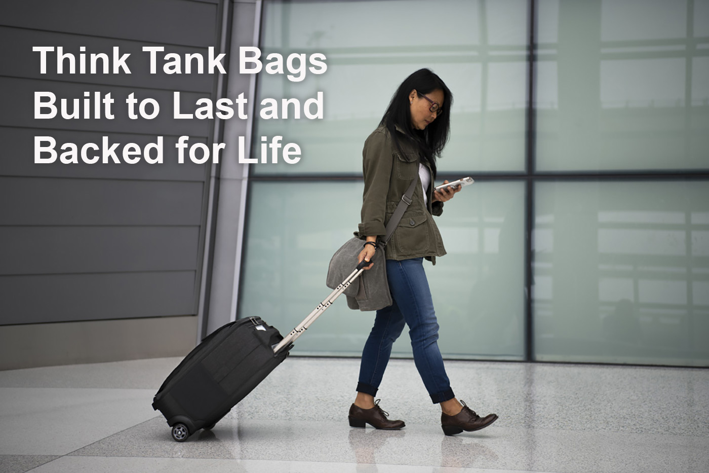 Think Tank Bags Built to Last and Backed for Life depicting woman walking through airport with rolling bag