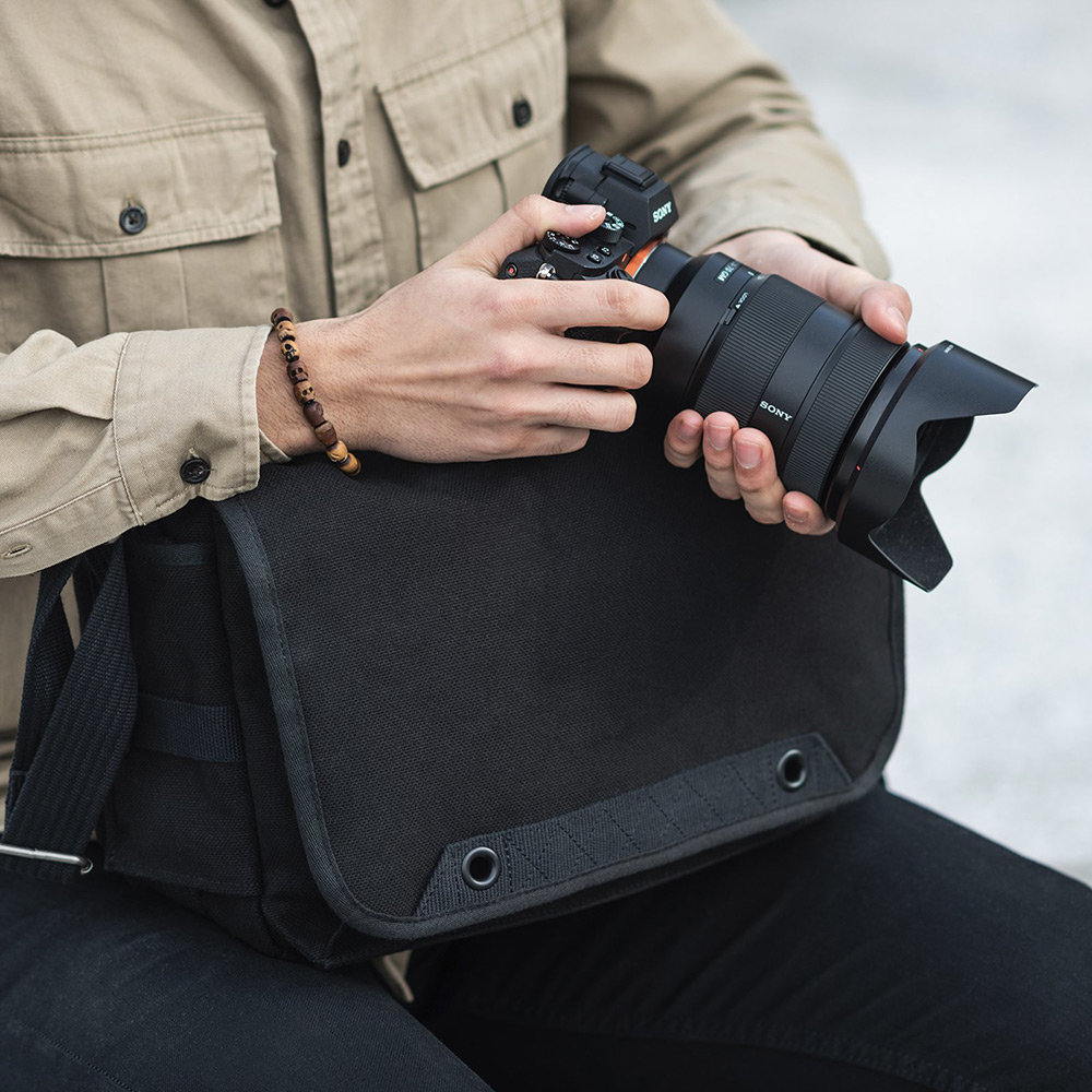 Black retro camera shoulder bag by Think Tank with photographer holding camera